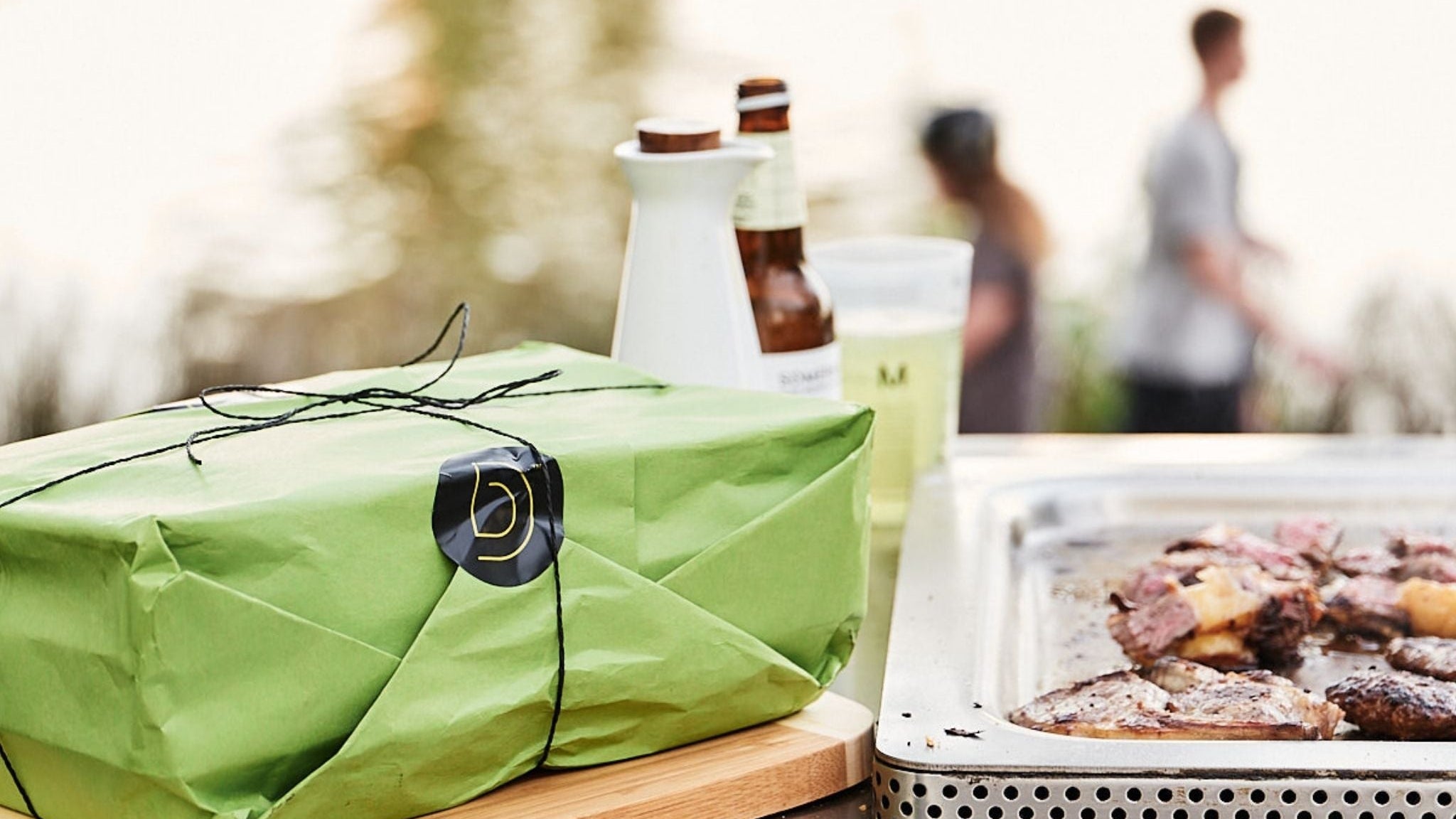 Green wrapped Digital Butcher Co. order on a public BBQ by Yarra River with people in the background